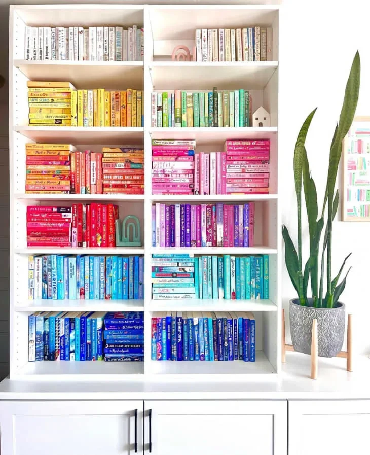 White bookshelves with books organized by color 1