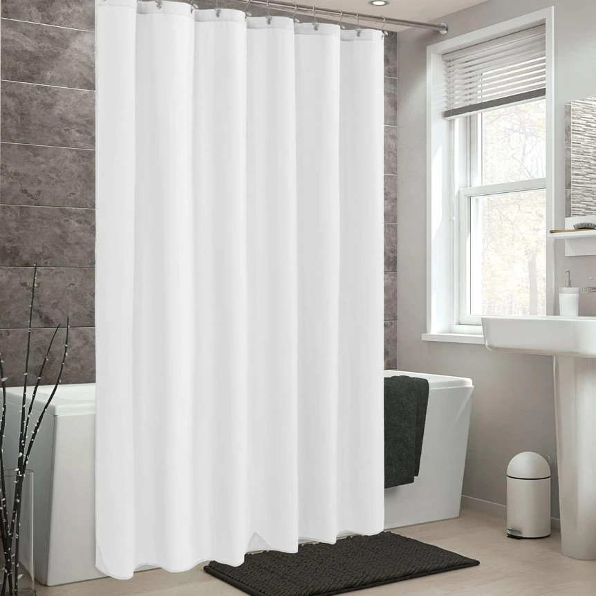 White shower curtain in modern bathroom with gray tile walls and black bath mat