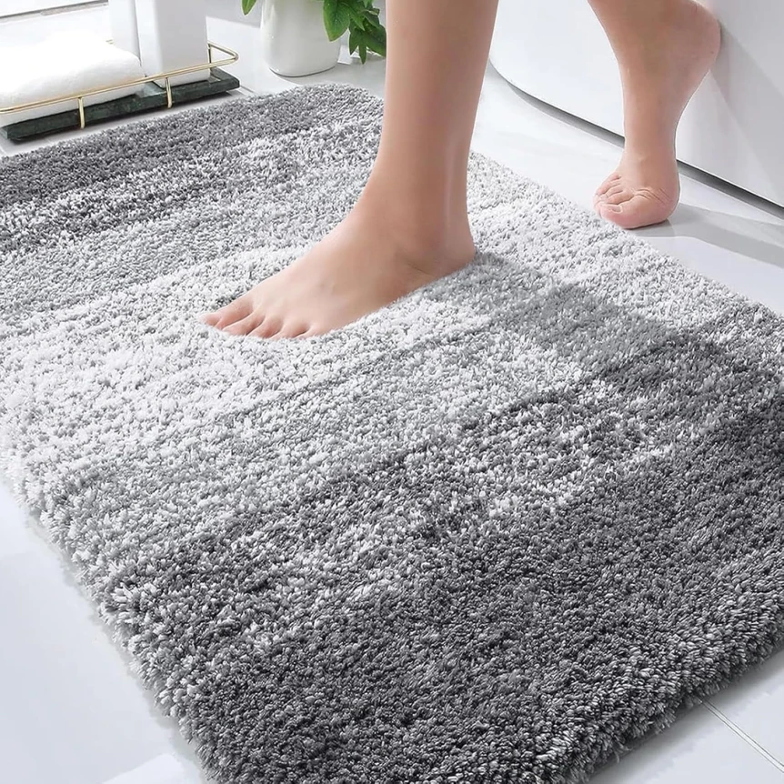 Person standing barefoot on plush gray striped bathroom rug in modern white bathroom
