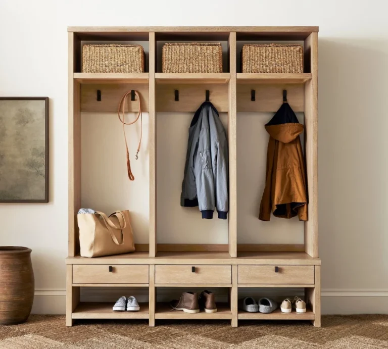Wooden mudroom storage unit with hooks, drawers, baskets and shoe cubbies organizing coats and footwear