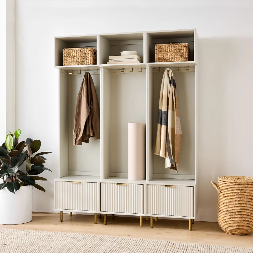 Modern mudroom storage unit with open cubbies, hanging rods for coats, wicker baskets, and white cabinet doors